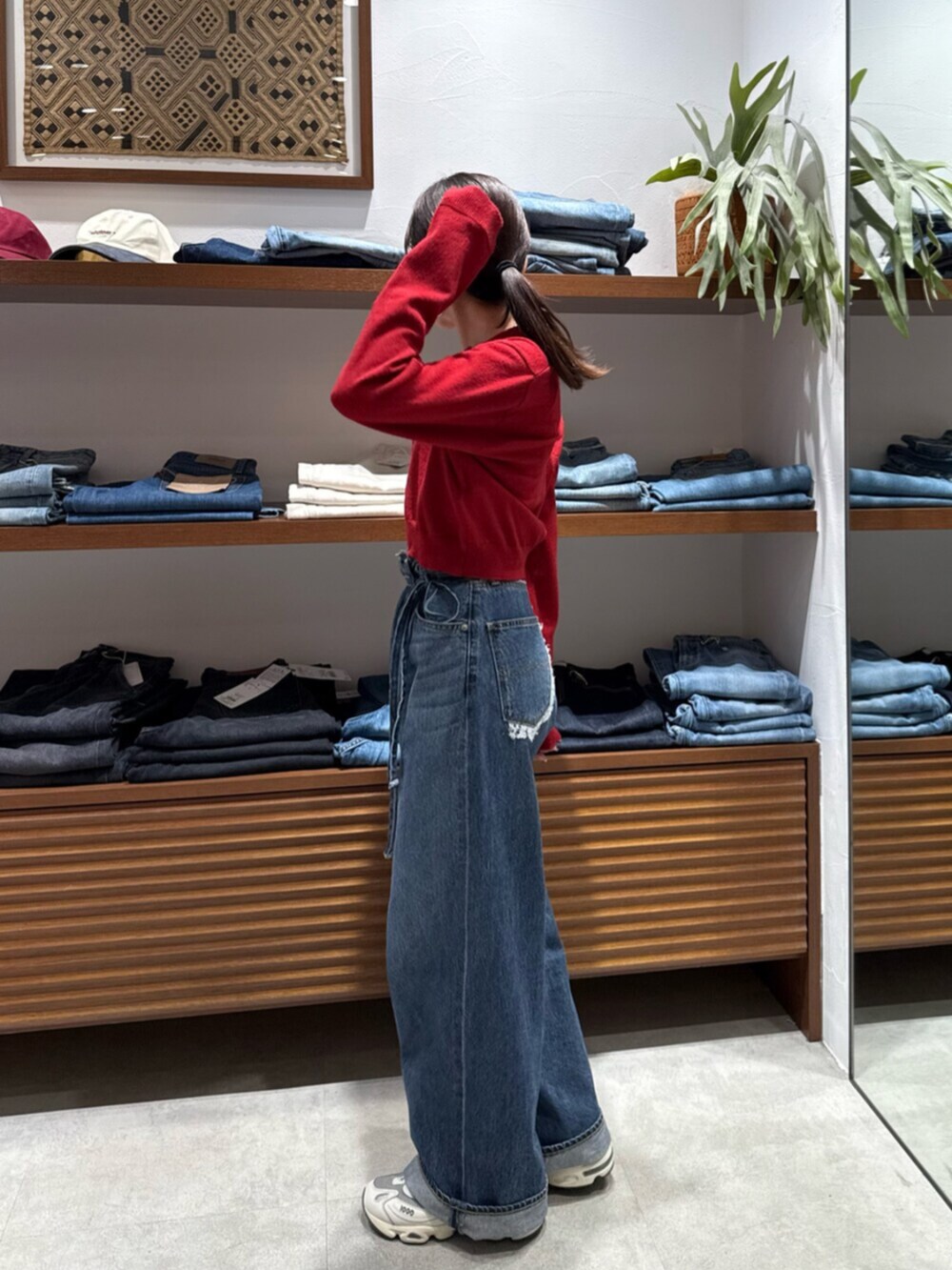 レッド系のカーディガン/ボレロ、ブルー系のデニムパンツを着用したレディースの秋コーディネートの4枚目の写真