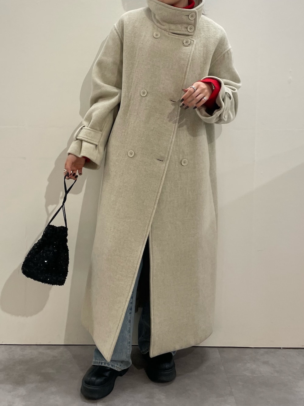 ブルー系のデニムパンツ、ブラック系のブーツ、レッド系のニット/セーターを着用したレディースの冬コーディネートの3枚目の写真