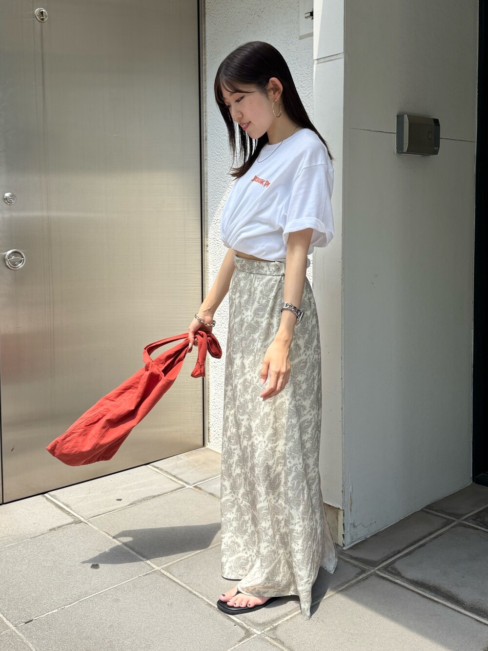 オレンジ系のトートバッグ、ホワイト系のTシャツ/カットソー、ブラック系のサンダルを着用したレディースの夏コーディネートの3枚目の写真