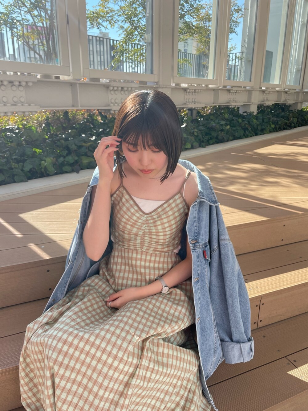 ホワイト系のハンドバッグ、グリーン系のワンピース、ブルー系のデニムジャケットを着用したレディースの冬コーディネートの7枚目の写真