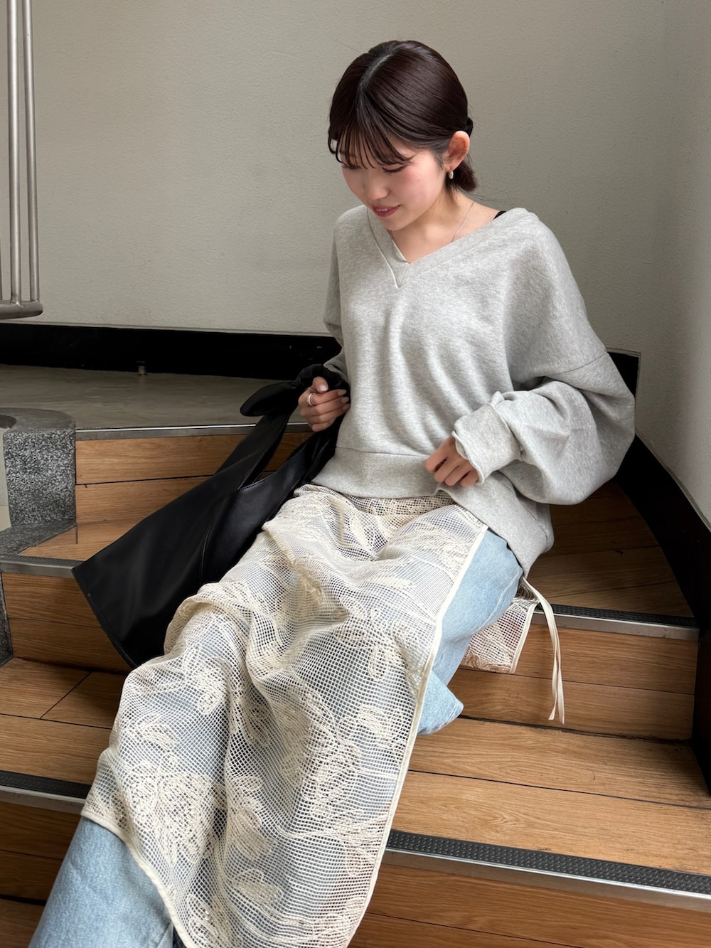 ブラック系のハンドバッグ、ブラック系のブーツ、ブルー系のデニムパンツを着用したレディースの春コーディネートの3枚目の写真