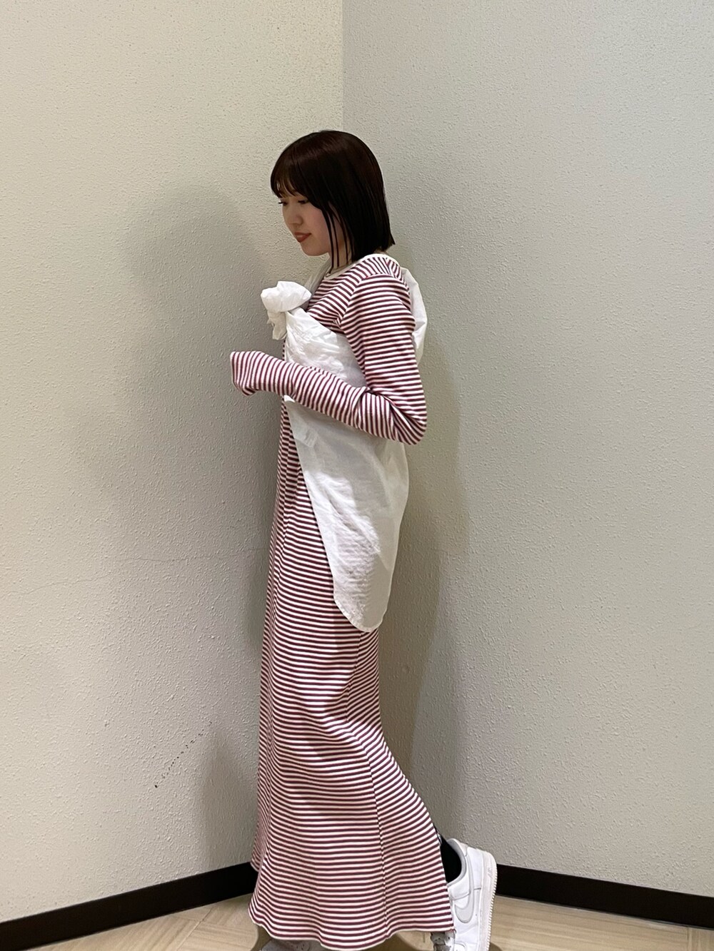 レッド系のワンピース、ホワイト系のシャツ/ブラウス、シルバー系のネックレスを着用したレディースの春コーディネートの2枚目の写真