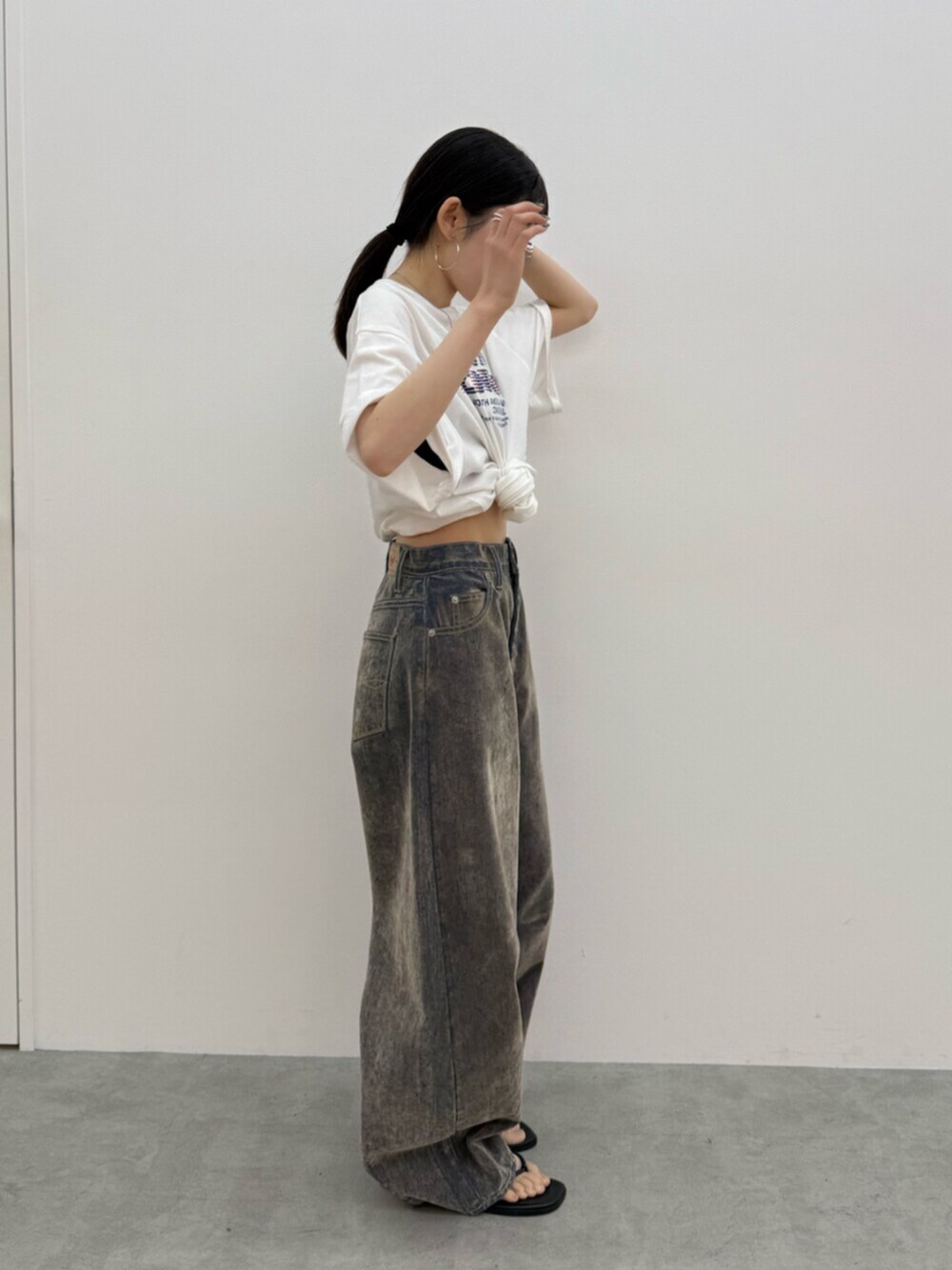 ブラック系のサンダル、ホワイト系のTシャツ/カットソー、ベージュ系のデニムパンツを着用したレディースの夏コーディネートの6枚目の写真