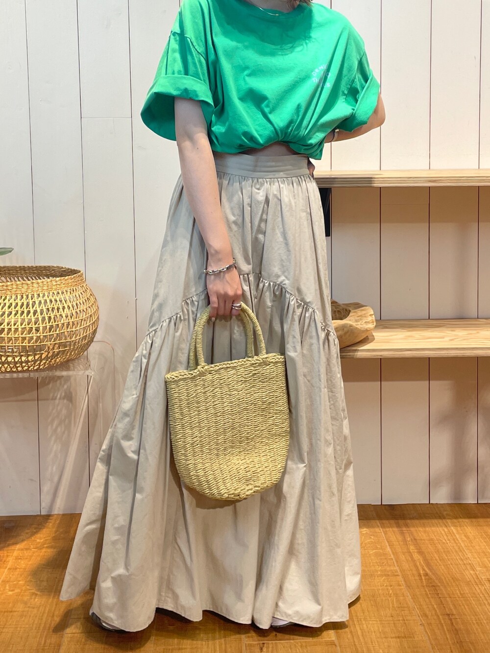 グリーン系のTシャツ/カットソー、ホワイト系のスカート、ベージュ系のかごバッグを着用したレディースの夏コーディネートの7枚目の写真