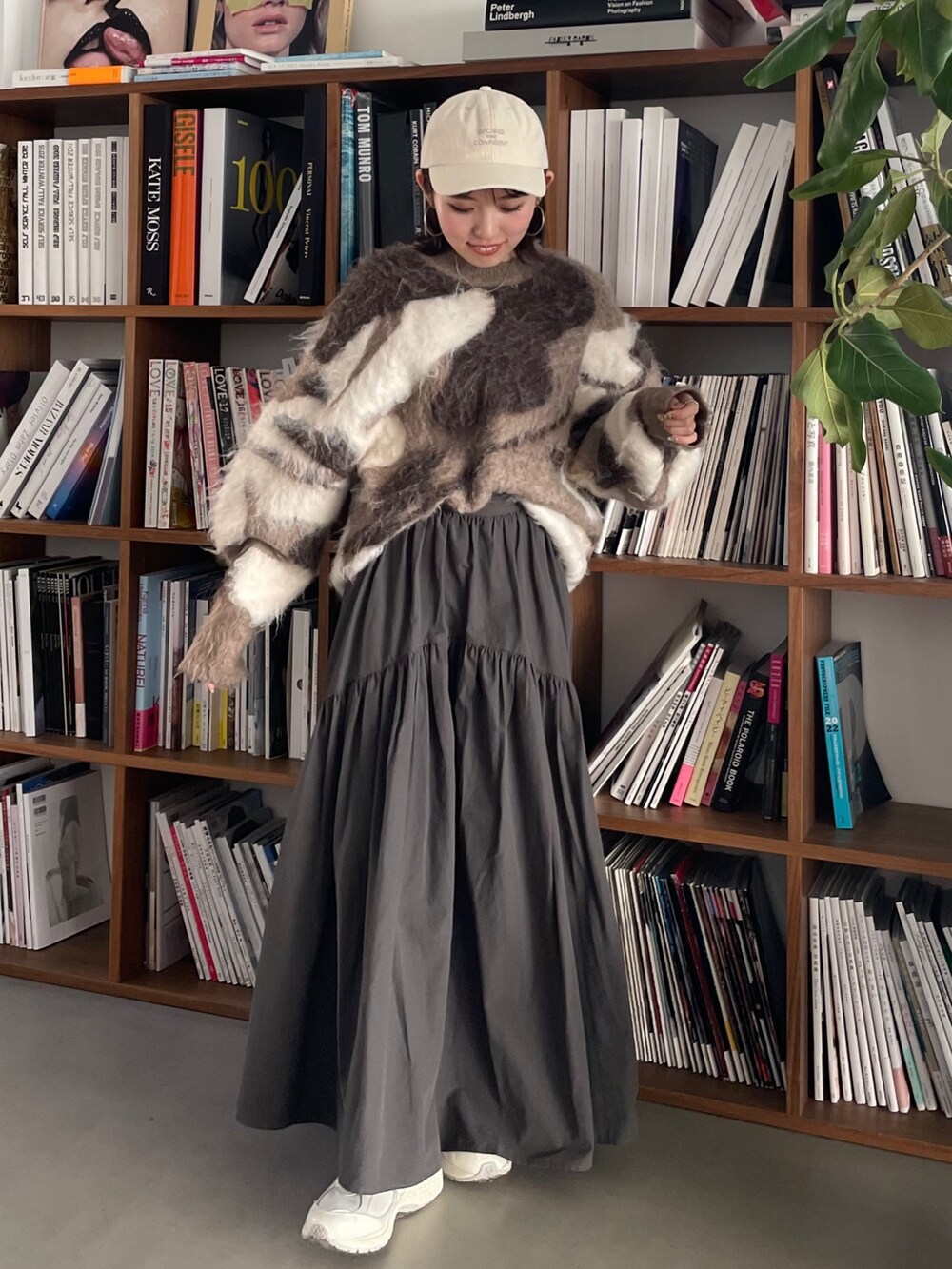 グレー系のスカート、ベージュ系のニット/セーター、ホワイト系のキャップを着用したレディースの秋コーディネートの6枚目の写真