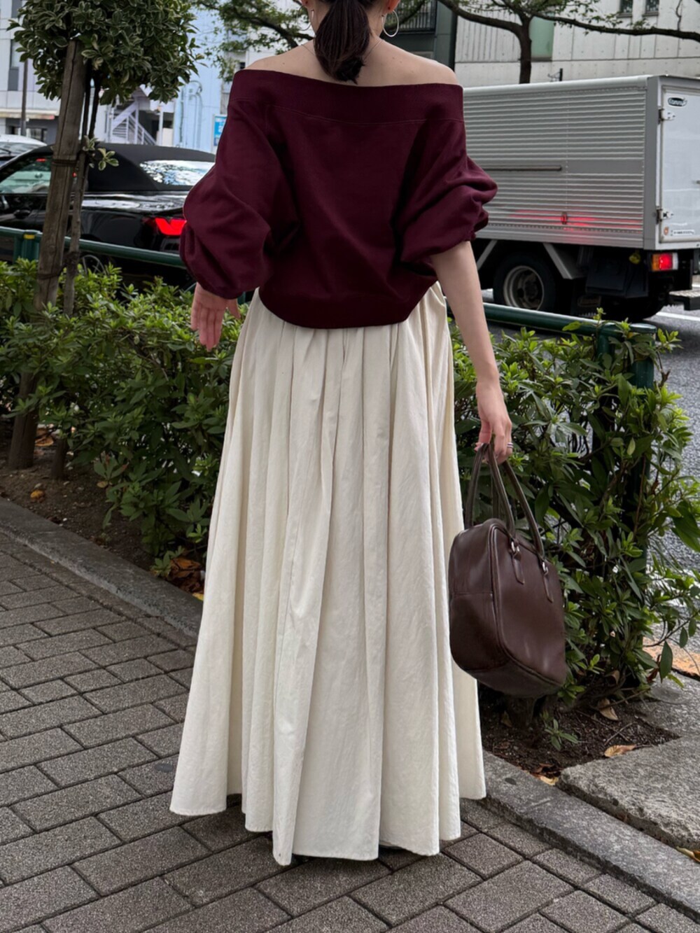 ブラウン系のハンドバッグ、ホワイト系のスカート、レッド系のスウェットを着用したレディースの秋コーディネートの3枚目の写真