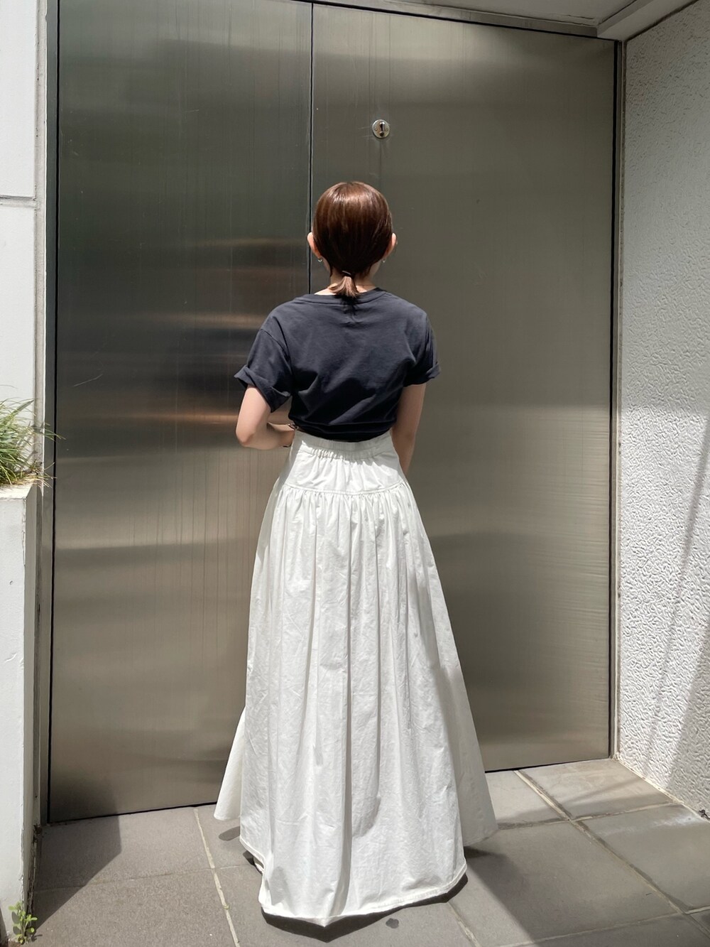 ホワイト系のスカート、グレー系のTシャツ/カットソー、ゴールド系のネックレスを着用したレディースの春コーディネートの3枚目の写真