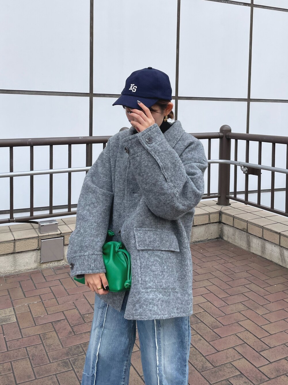 ブルー系のデニムパンツ、ホワイト系のブーツ、グリーン系のクラッチバッグを着用したレディースの秋コーディネートの7枚目の写真