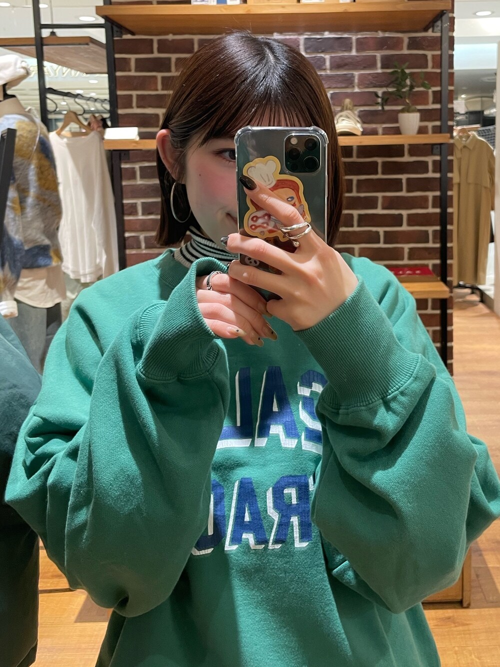 グレー系のスカート、グリーン系のスウェット、ホワイト系のニット/セーターを着用したレディースの冬コーディネートの6枚目の写真