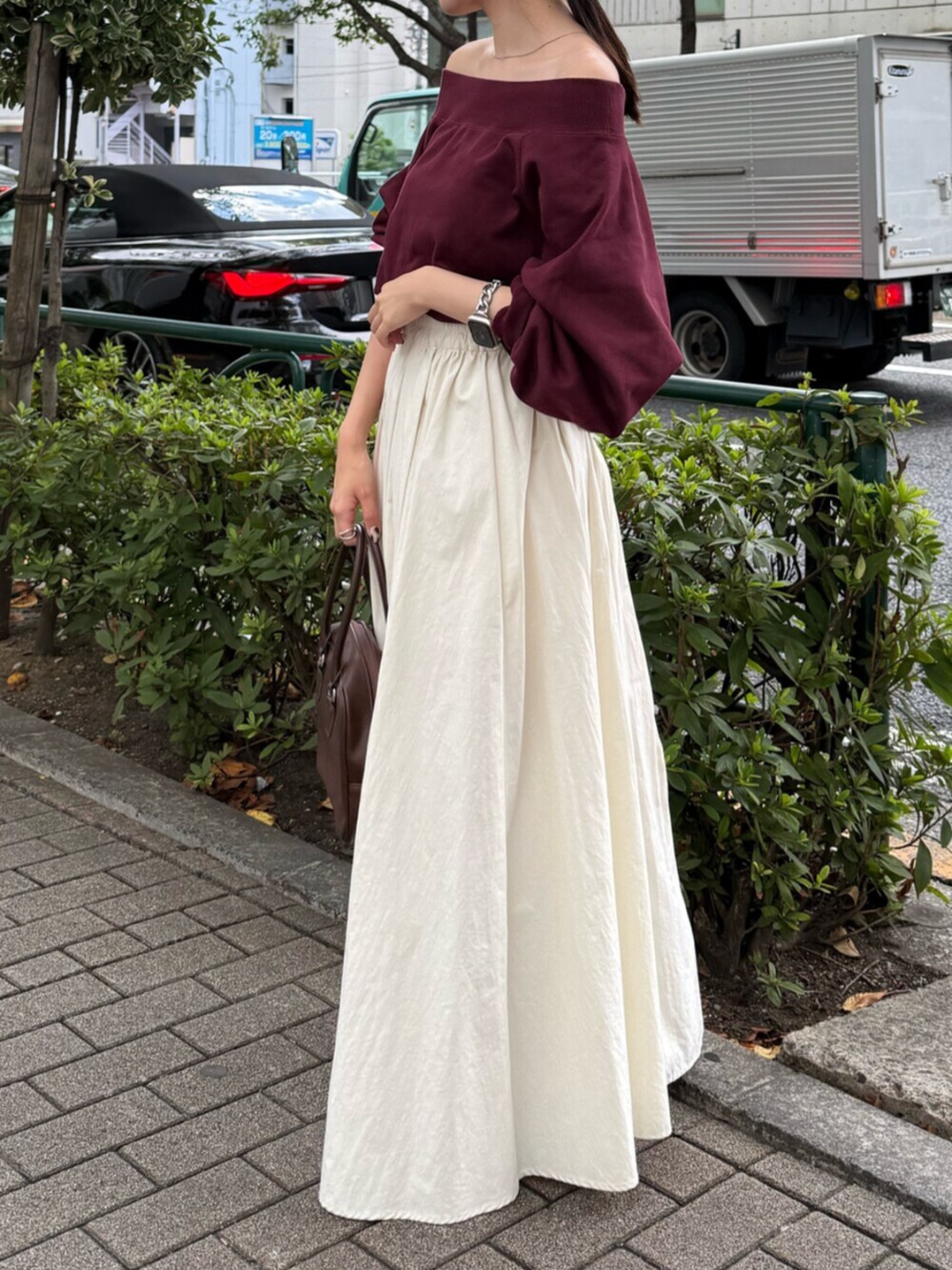 ブラウン系のハンドバッグ、ホワイト系のスカート、レッド系のスウェットを着用したレディースの秋コーディネートの5枚目の写真