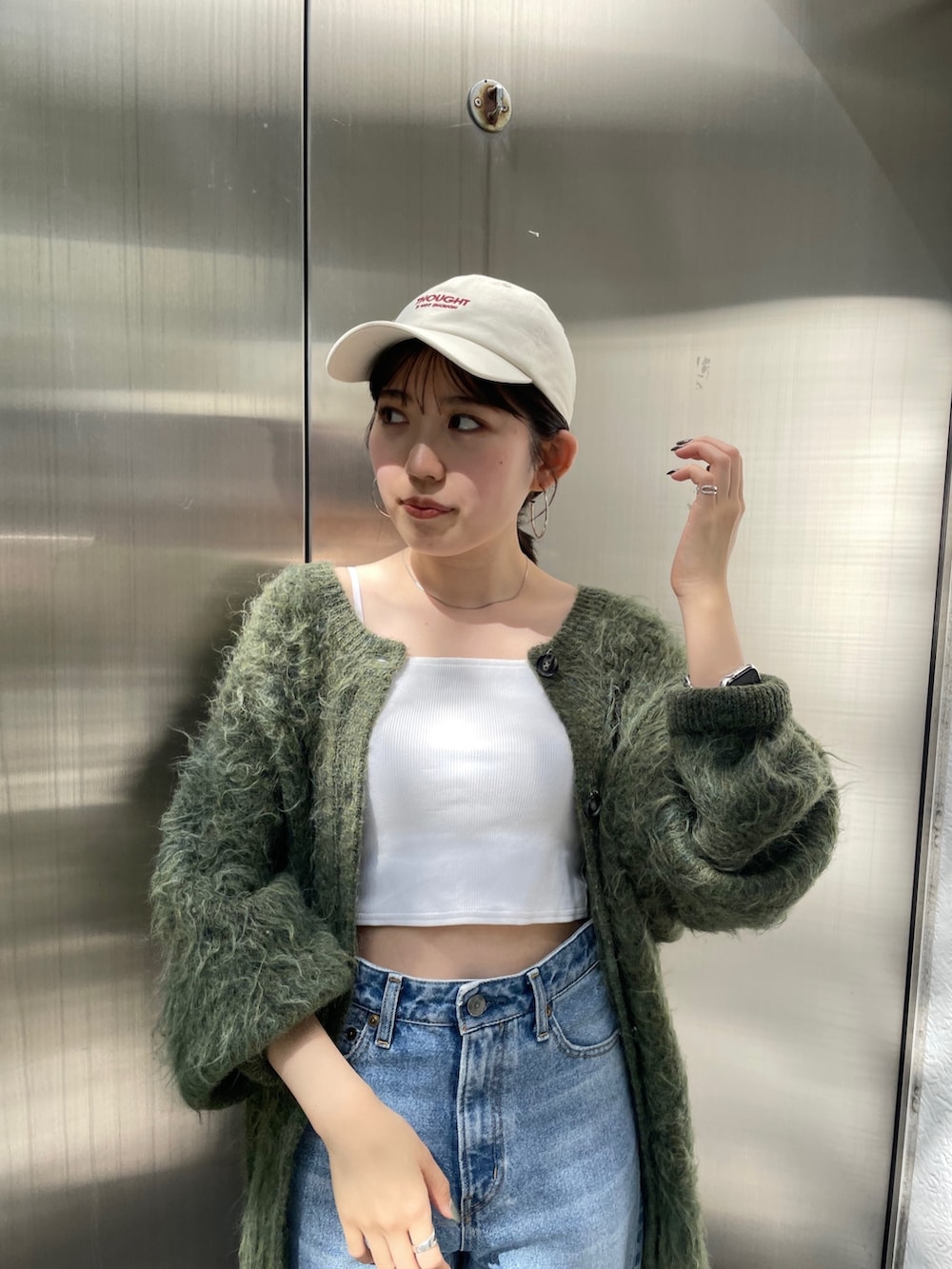 グリーン系のカーディガン/ボレロ、ベージュ系のブーツ、ブルー系のデニムパンツを着用したレディースの秋コーディネートの2枚目の写真