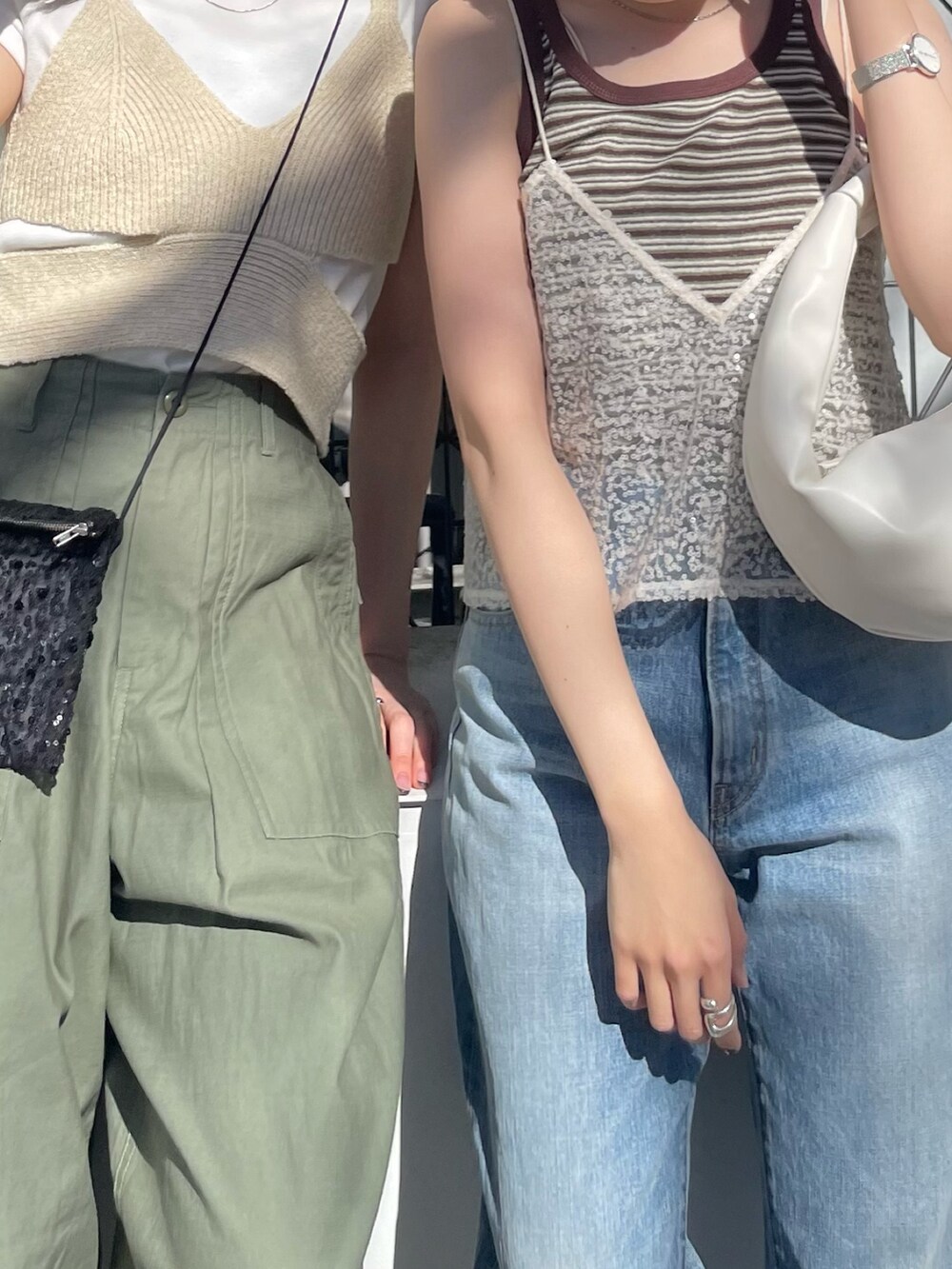 ホワイト系のハンドバッグ、ブルー系のデニムパンツ、ホワイト系のキャミソールを着用したレディースの春コーディネートの5枚目の写真