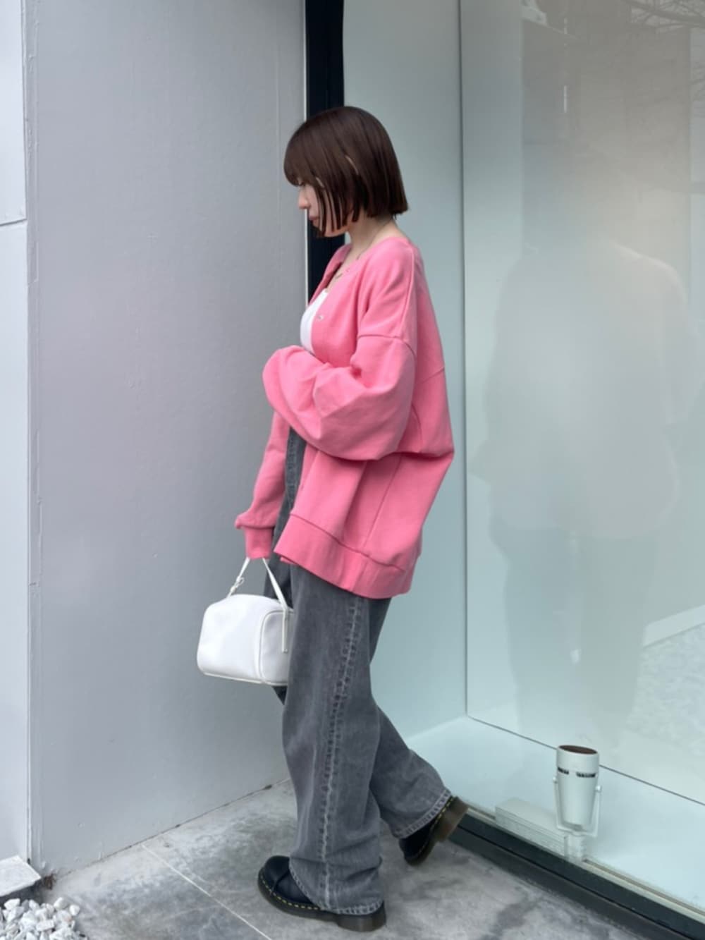 ピンク系のカーディガン/ボレロ、ホワイト系のハンドバッグ、ブラック系のデニムパンツを着用したレディースの冬コーディネートの2枚目の写真