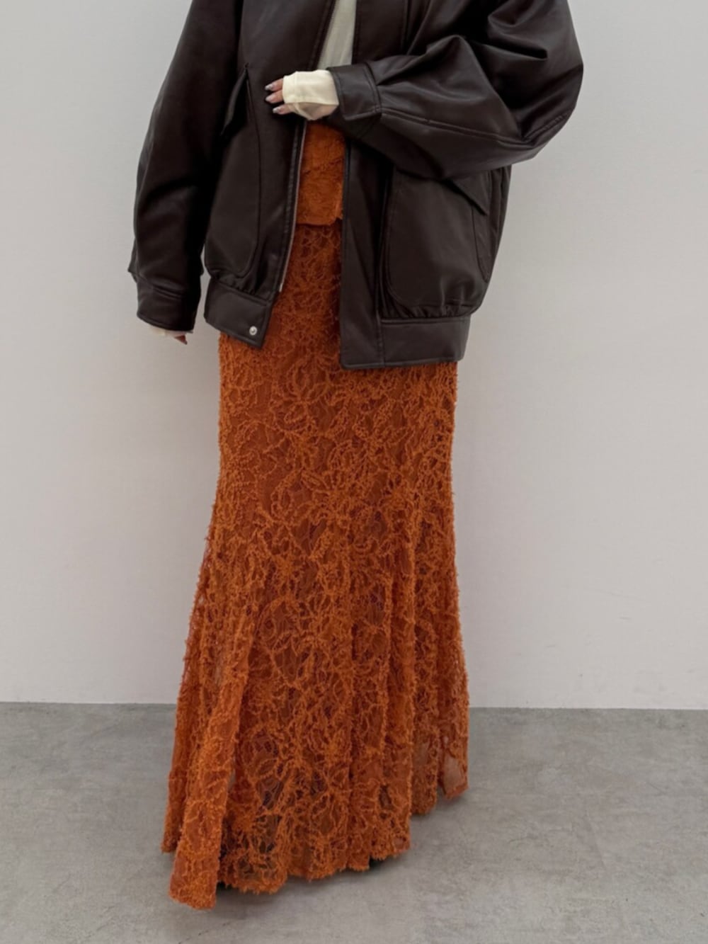 ブラック系のブーツ、ブラウン系のブルゾン、オレンジ系のスカートを着用したレディースの冬コーディネートの4枚目の写真