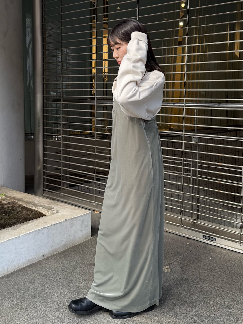 グレー系のワンピース、ホワイト系のスウェット、ブラック系のブーツを着用したレディースの冬コーディネートの2枚目の写真