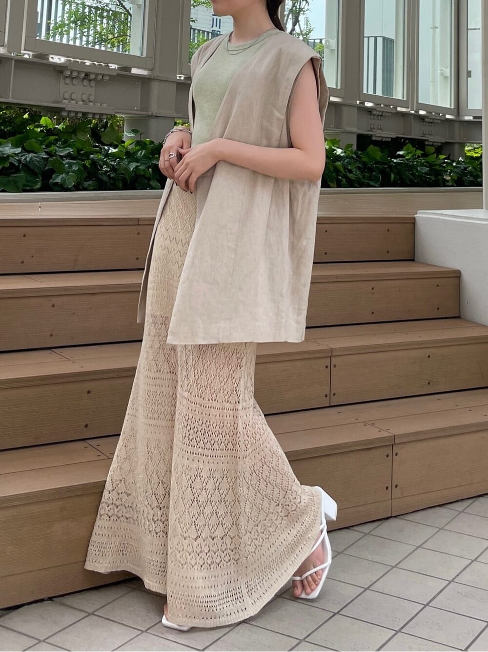 ベージュ系のスカート、ピンク系のハンドバッグ、グリーン系のタンクトップを着用したレディースの夏コーディネートの2枚目の写真