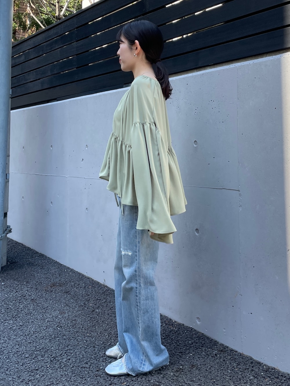 ブルー系のデニムパンツ、シルバー系のバレエシューズ、グリーン系のシャツ/ブラウスを着用したレディースの春コーディネートの2枚目の写真