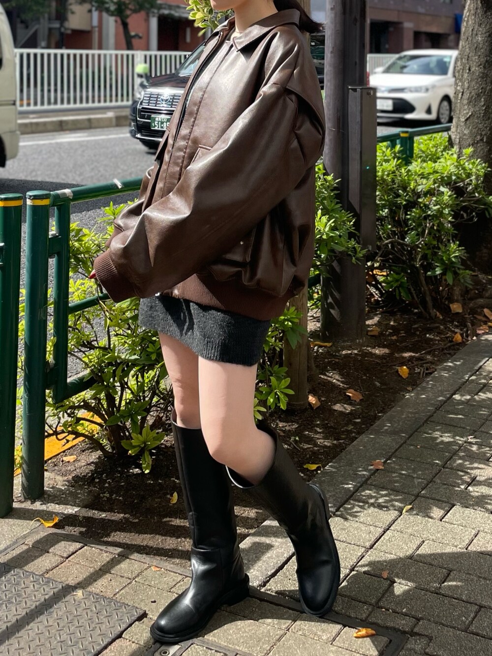 グレー系のスカート、ブラック系のブーツ、ブラウン系のブルゾンを着用したレディースの秋コーディネートの3枚目の写真