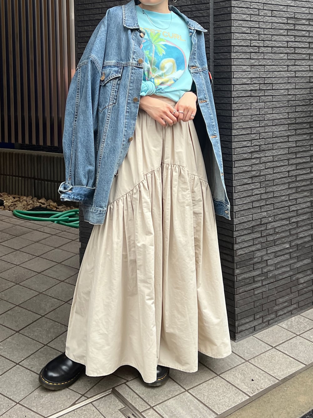 ホワイト系のスカート、ブラック系のブーツ、ブルー系のデニムジャケットを着用したレディースの春コーディネートの2枚目の写真