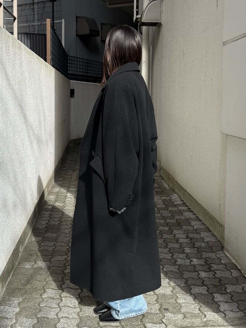 ブルー系のデニムパンツ、ブラック系のブーツ、ブラック系のチェスターコートを着用したレディースの冬コーディネートの2枚目の写真