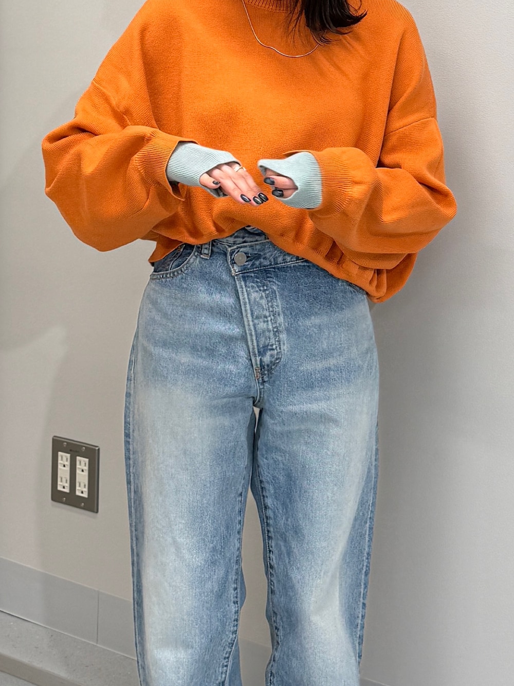 ブルー系のデニムパンツ、オレンジ系のニット/セーター、ブラック系のブーツを着用したレディースの冬コーディネートの5枚目の写真