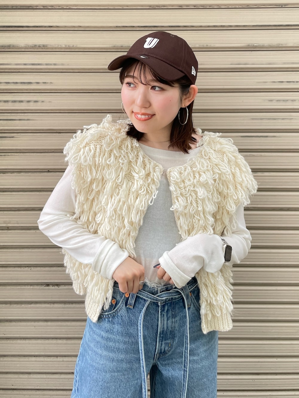 ホワイト系のサンダル、ブルー系のデニムパンツ、ホワイト系のベストを着用したレディースの夏コーディネートの5枚目の写真