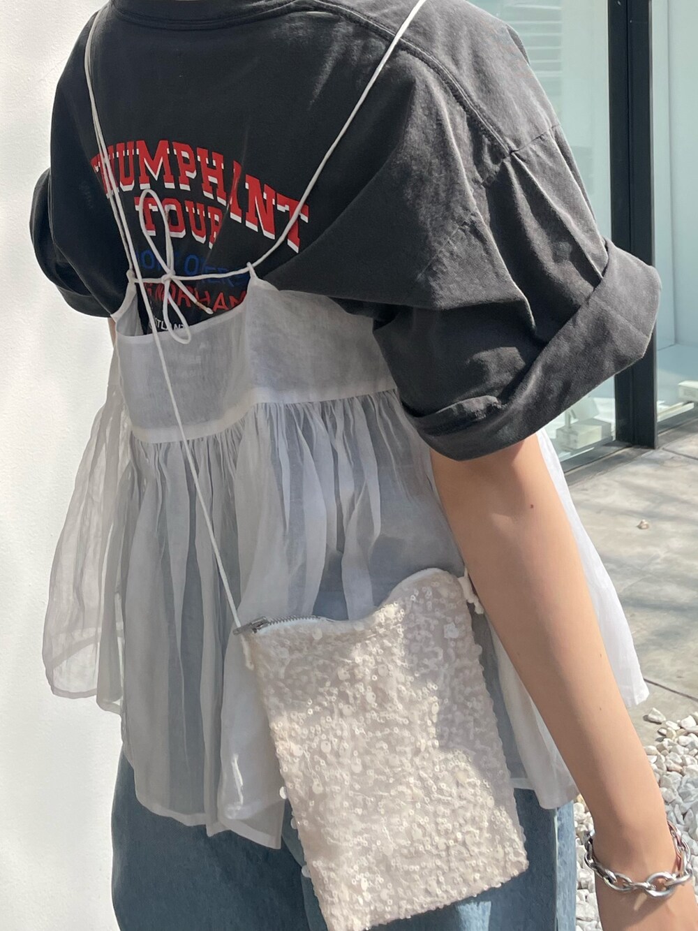 ブルー系のデニムパンツ、グレー系のTシャツ/カットソー、ホワイト系のショルダーバッグを着用したレディースの春コーディネートの7枚目の写真