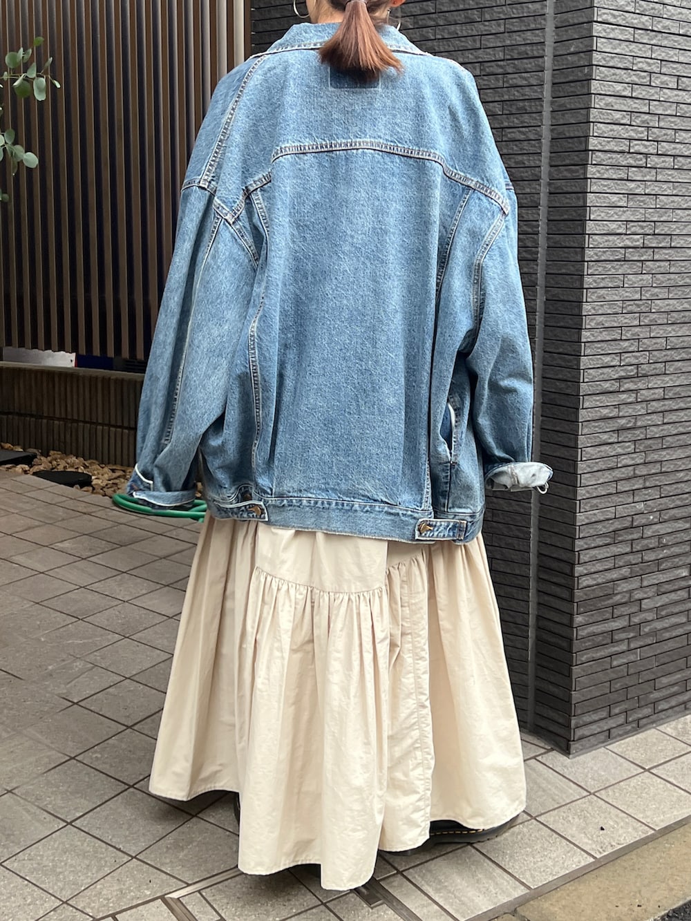 ホワイト系のスカート、ブラック系のブーツ、ブルー系のデニムジャケットを着用したレディースの春コーディネートの10枚目の写真