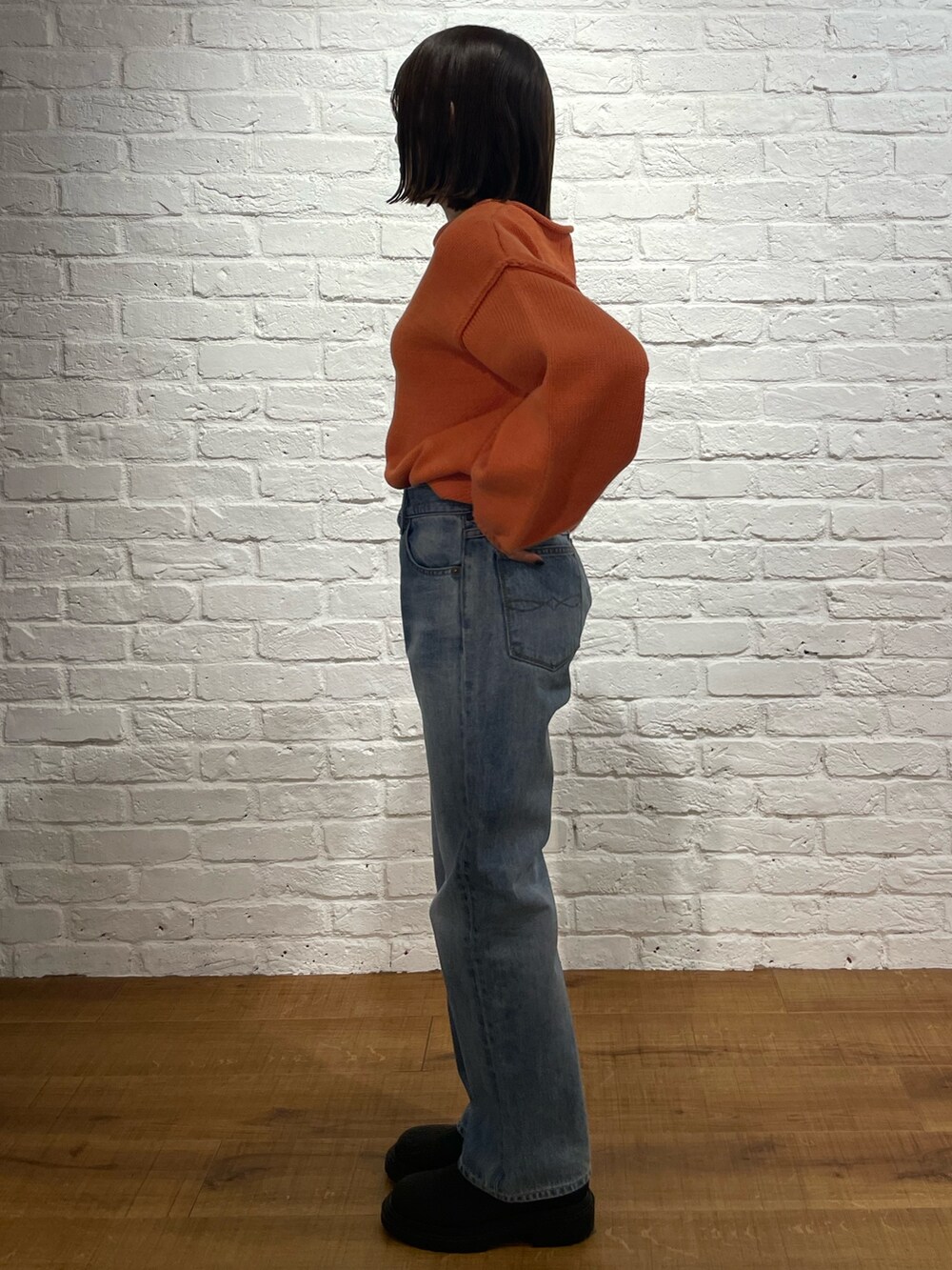 オレンジ系のニット/セーター、ブルー系のデニムパンツ、ブラック系のブーツを着用したレディースの冬コーディネートの3枚目の写真