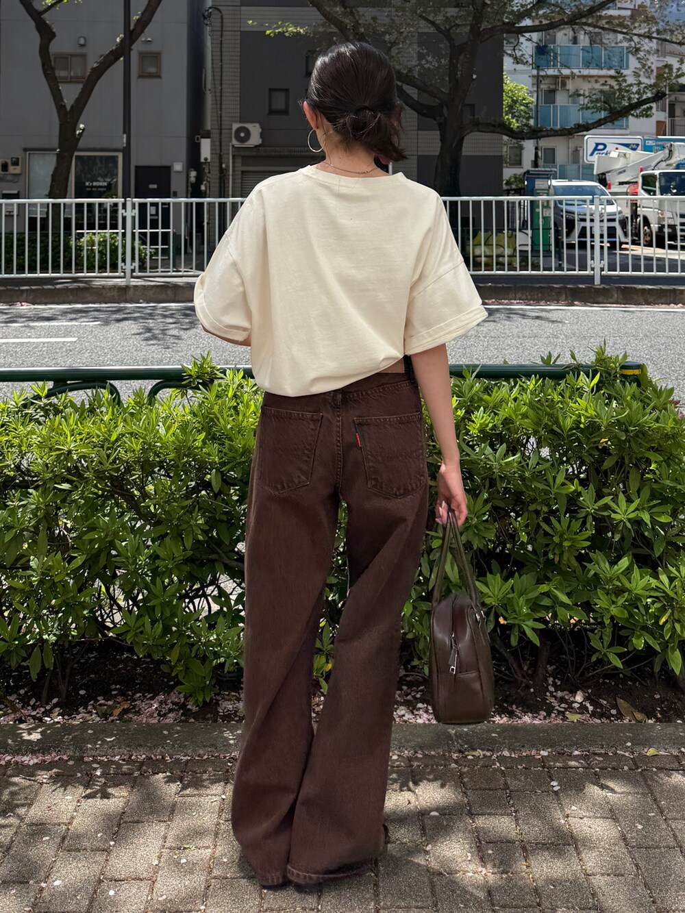 ホワイト系のTシャツ/カットソー、ブラウン系のデニムパンツ、ブラック系のサンダルを着用したレディースの春コーディネートの2枚目の写真