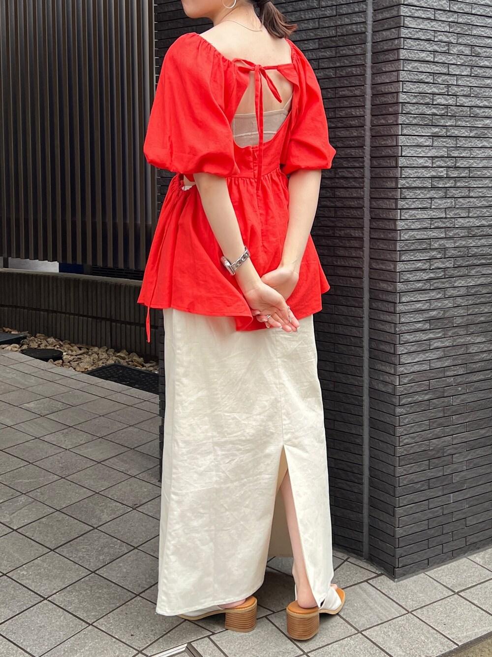 グレー系のキャミソール、ホワイト系のスカート、ホワイト系のサンダルを着用したレディースの春コーディネートの4枚目の写真