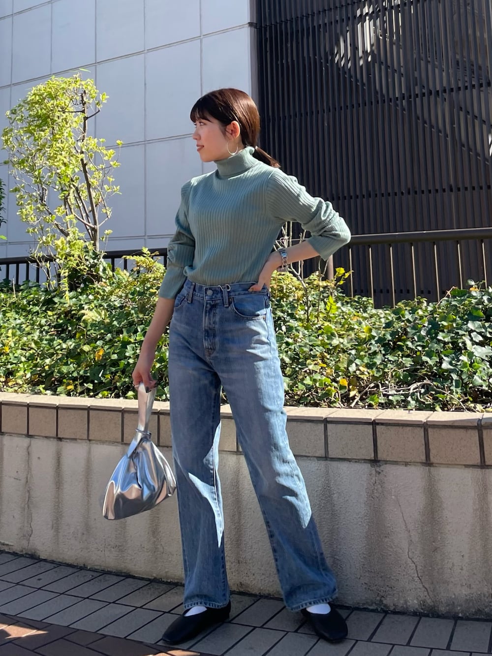 ブラウン系のブルゾン、ブラック系のパンプス、ブルー系のデニムパンツを着用したレディースの秋コーディネートの6枚目の写真