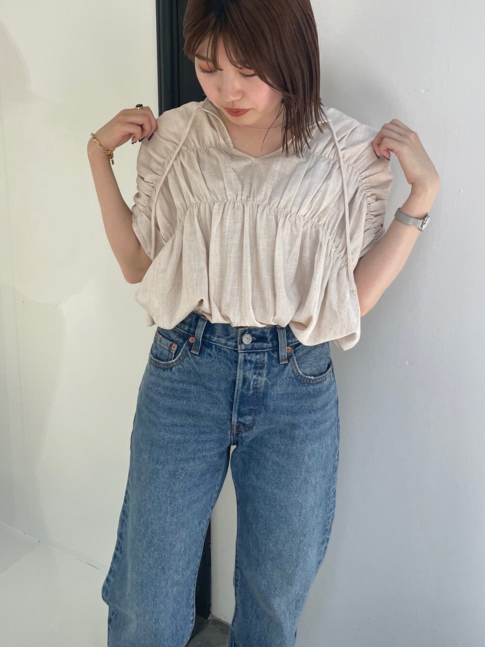 ホワイト系のシャツ/ブラウス、ブラック系のスニーカー、ブルー系のデニムパンツを着用したレディースの夏コーディネートの3枚目の写真