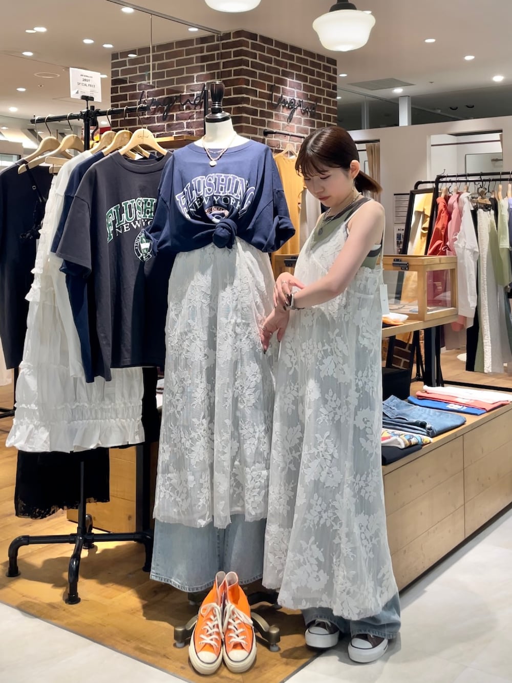 グリーン系のタンクトップ、ブルー系のデニムパンツ、ホワイト系のワンピースを着用したレディースの夏コーディネートの3枚目の写真