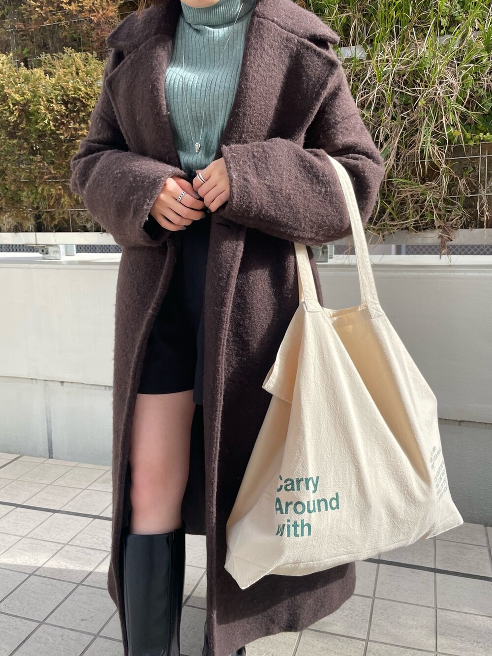 グリーン系のニット/セーター、ブラウン系のチェスターコート、ホワイト系のハンドバッグを着用したレディースの冬コーディネートの9枚目の写真