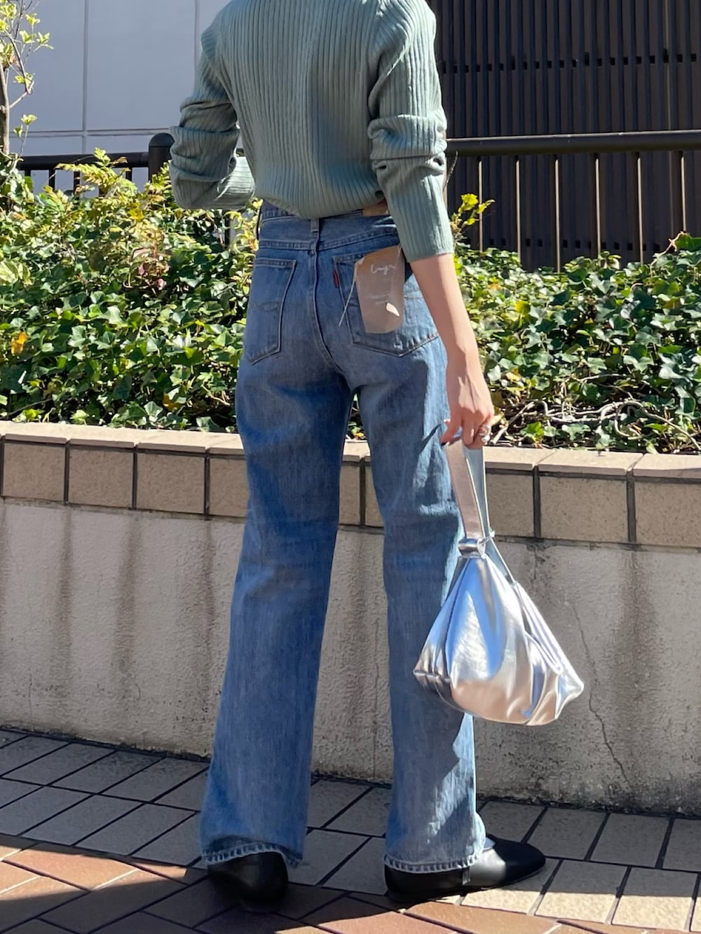 ブラウン系のブルゾン、ブラック系のパンプス、ブルー系のデニムパンツを着用したレディースの秋コーディネートの7枚目の写真