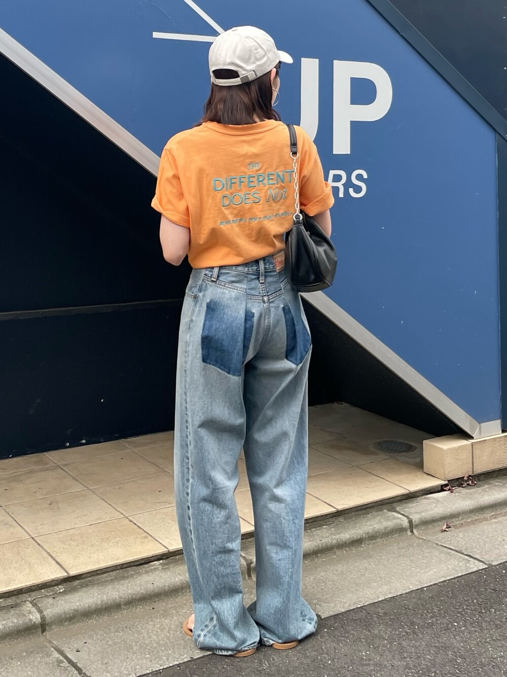ブラック系のサンダル、ブルー系のデニムパンツ、オレンジ系のTシャツ/カットソーを着用したレディースの夏コーディネートの5枚目の写真