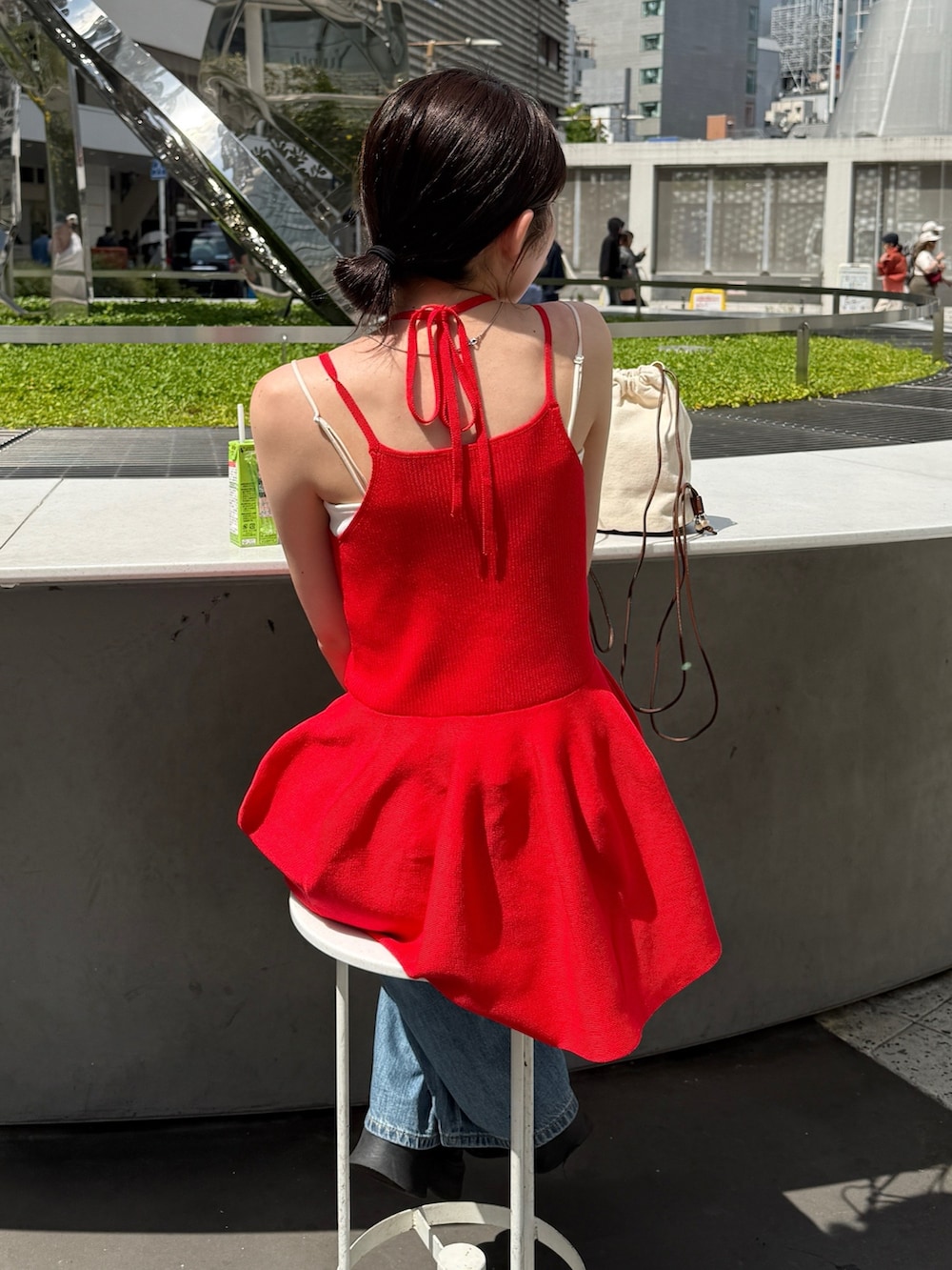 レッド系のキャミソール、ブルー系のデニムパンツ、ブラック系のブーツを着用したレディースの春コーディネートの3枚目の写真