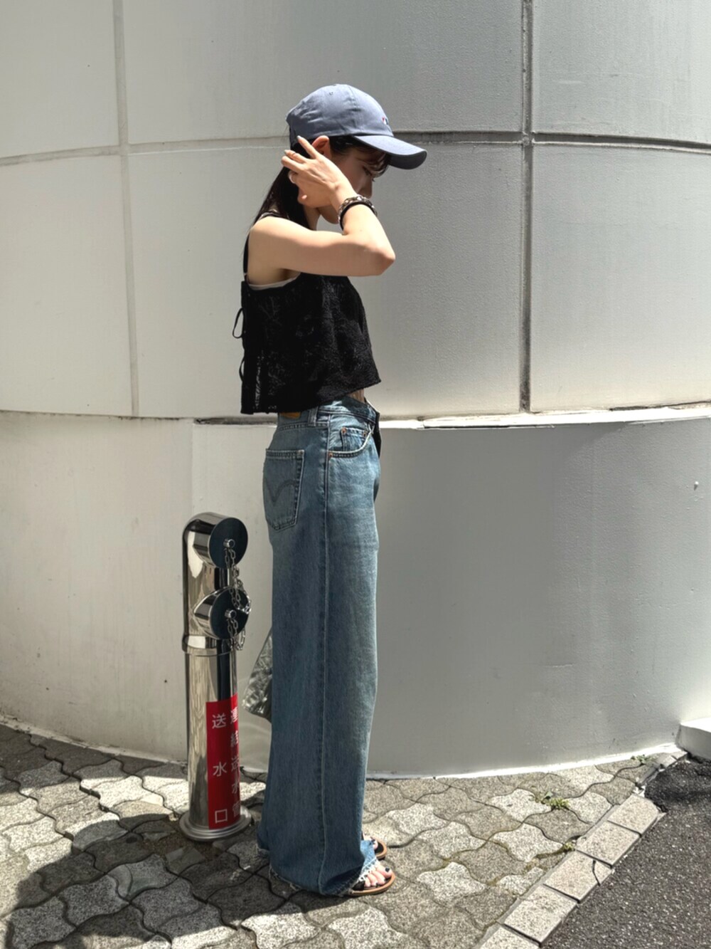 ブラック系のサンダル、グリーン系のトートバッグ、ブルー系のデニムパンツを着用したレディースの夏コーディネートの2枚目の写真