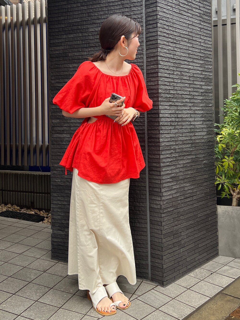 グレー系のキャミソール、ホワイト系のスカート、ホワイト系のサンダルを着用したレディースの春コーディネートの3枚目の写真