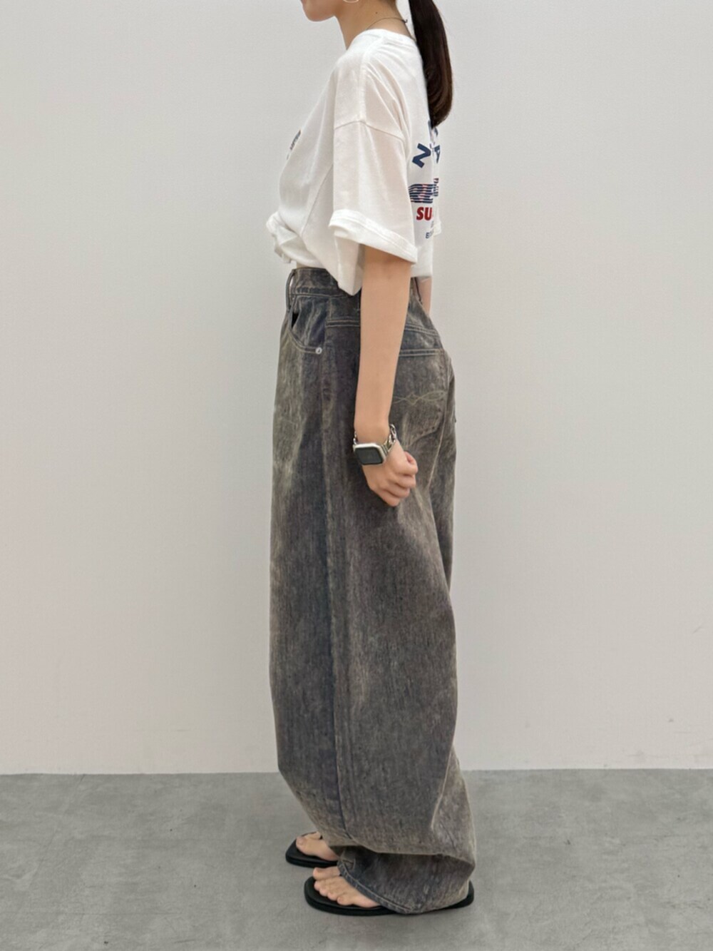 ブラック系のサンダル、ホワイト系のTシャツ/カットソー、ベージュ系のデニムパンツを着用したレディースの夏コーディネートの2枚目の写真