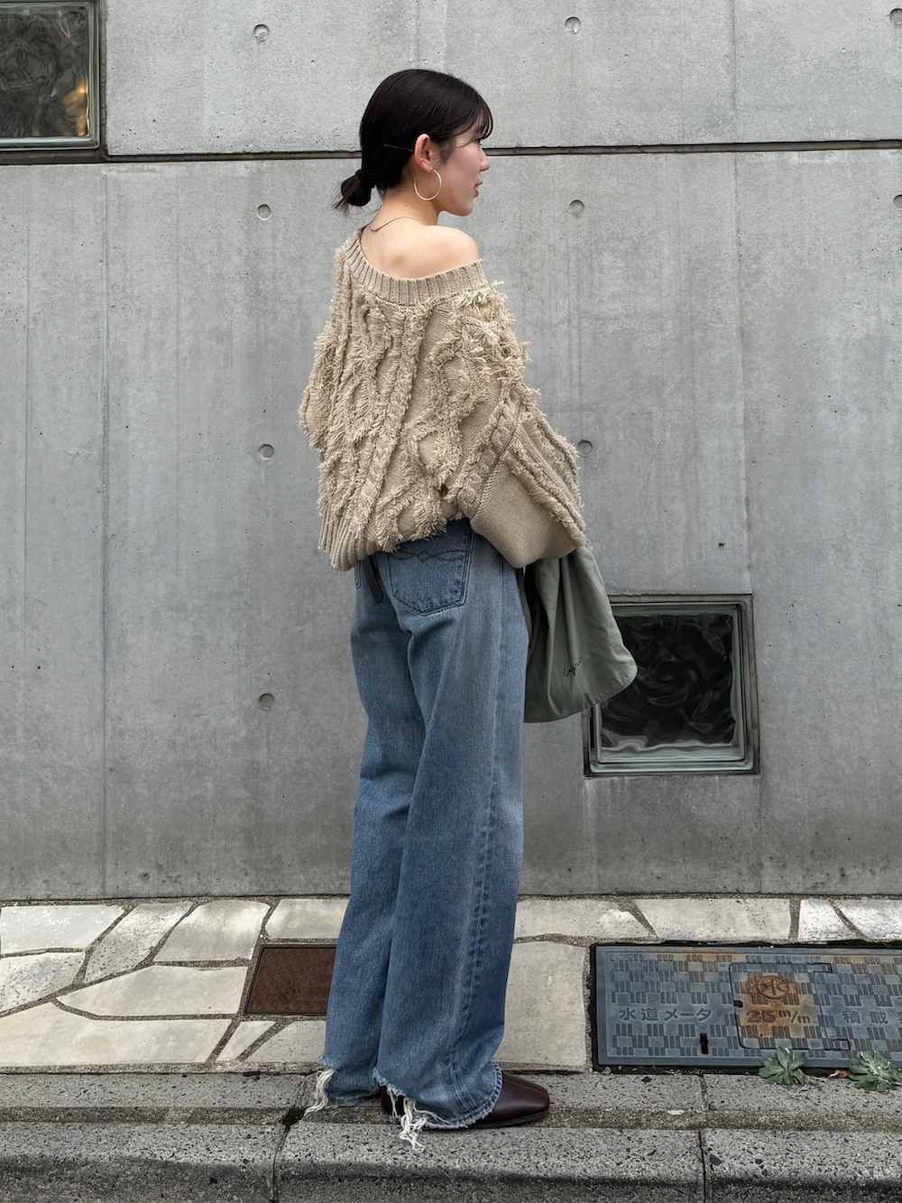 ブルー系のデニムパンツ、グリーン系のトートバッグ、ブラウン系のブーツを着用したレディースの秋コーディネートの5枚目の写真