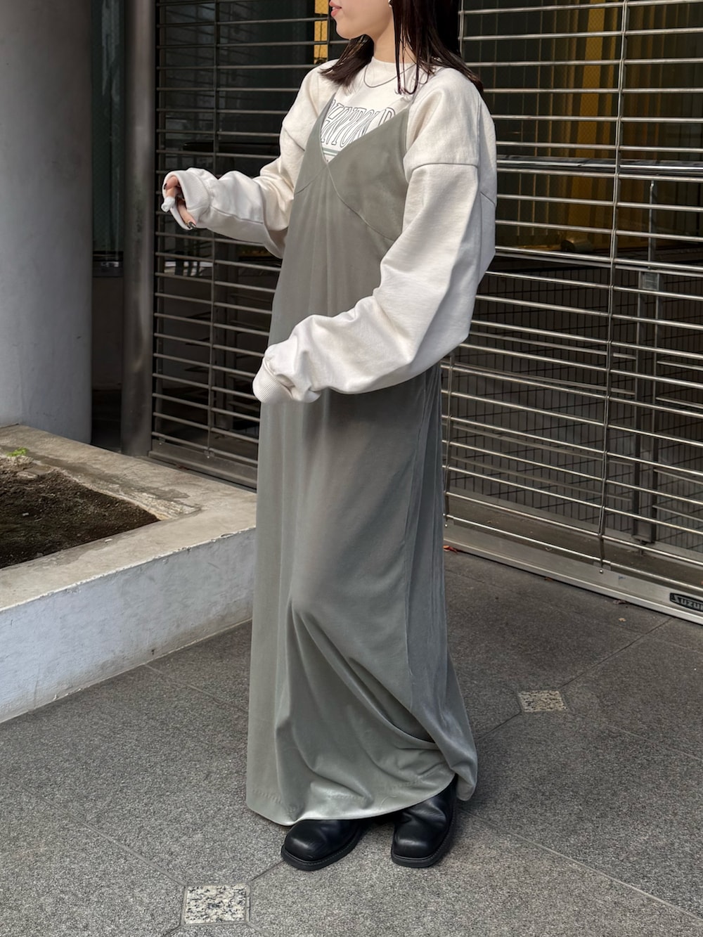 グレー系のワンピース、ホワイト系のスウェット、ブラック系のブーツを着用したレディースの冬コーディネートの3枚目の写真