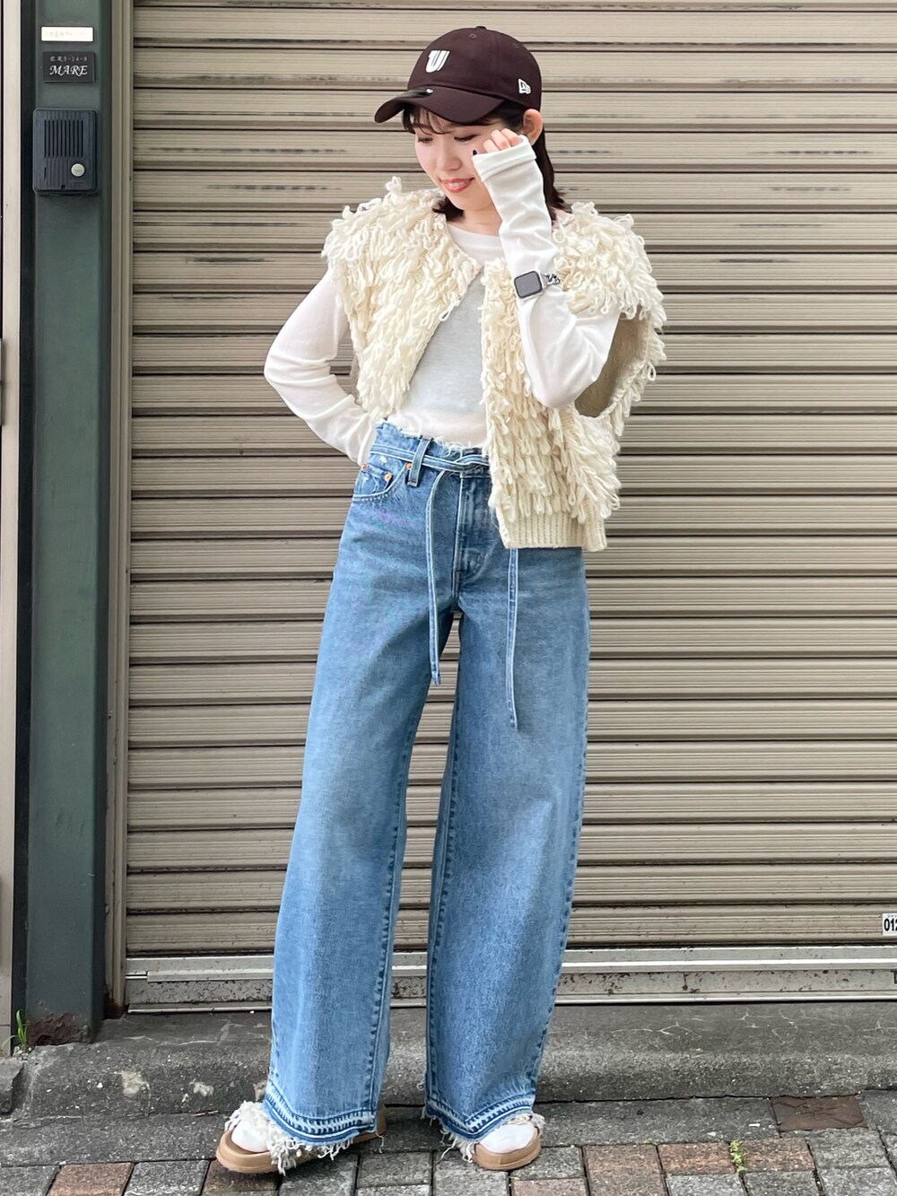 ホワイト系のサンダル、ブルー系のデニムパンツ、ホワイト系のベストを着用したレディースの夏コーディネートの2枚目の写真