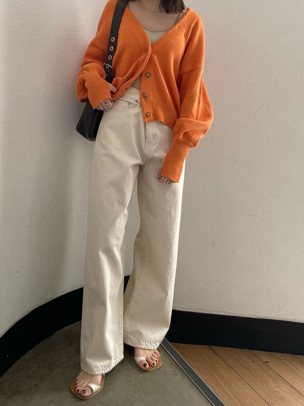 グレー系のキャミソール、ホワイト系のデニムパンツ、ホワイト系のサンダルを着用したレディースの春コーディネートの6枚目の写真