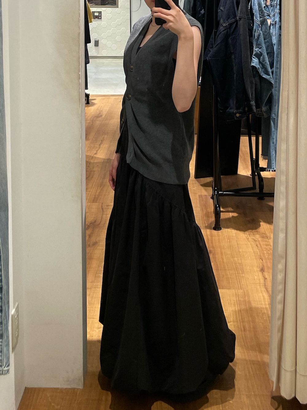 ブラック系のスカート、ブラック系のブーツ、グレー系のベストを着用したレディースの秋コーディネートの4枚目の写真