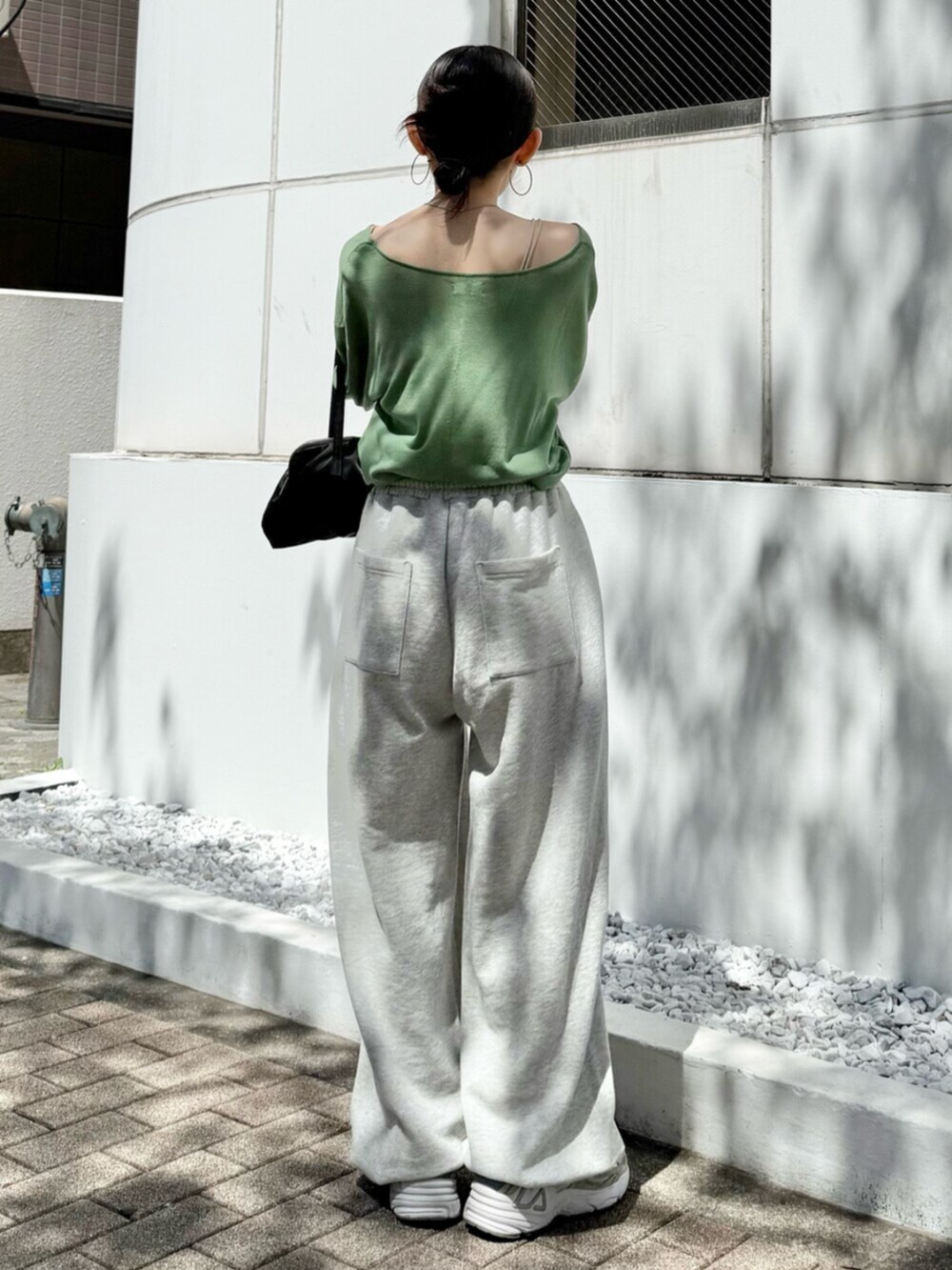 グレー系のスウェットパンツ、ブラック系のハンドバッグ、グリーン系のニット/セーターを着用したレディースの春コーディネートの6枚目の写真