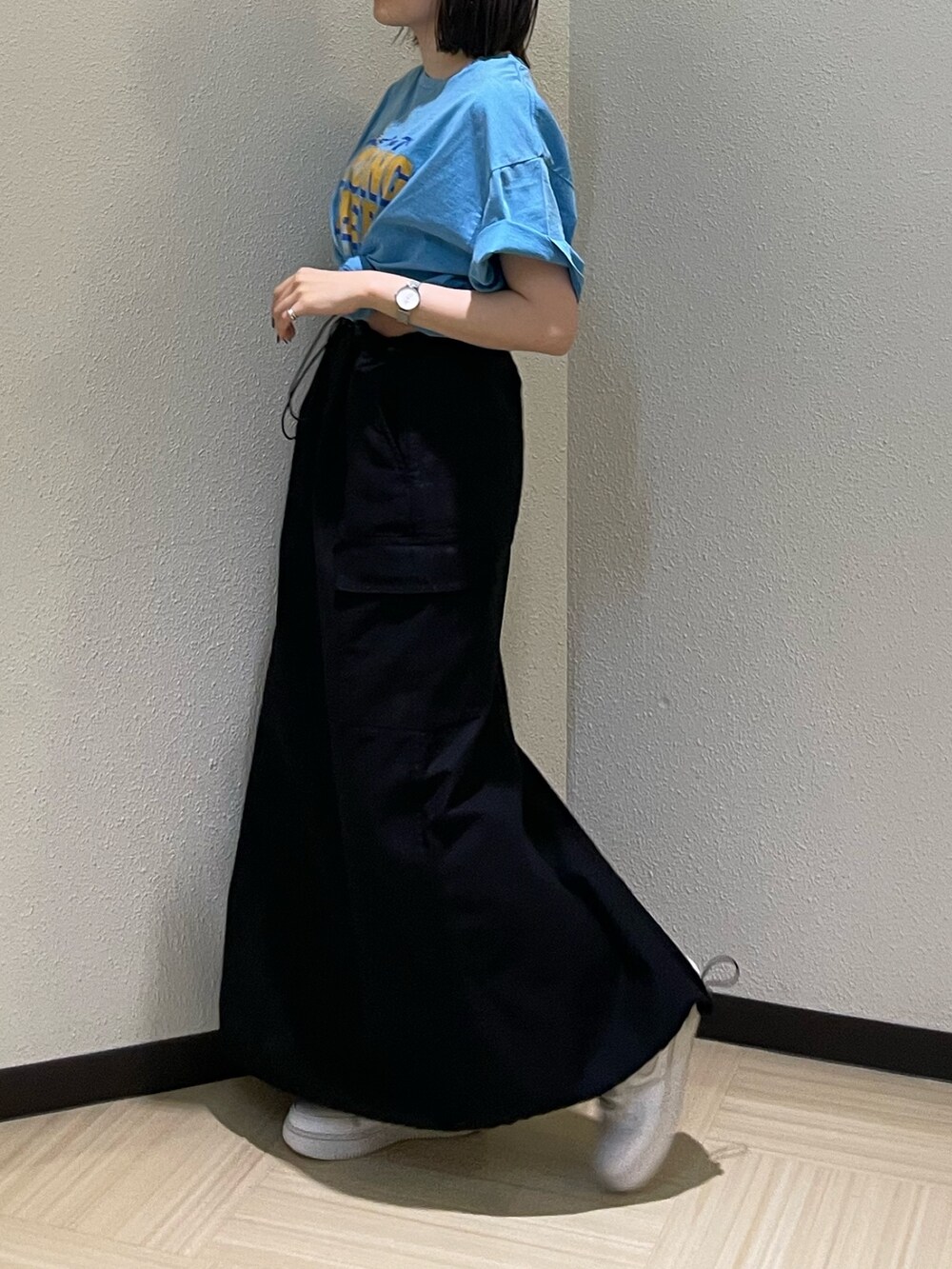 ブルー系のTシャツ/カットソー、ブラック系のスカート、ゴールド系のネックレスを着用したレディースの春コーディネートの3枚目の写真