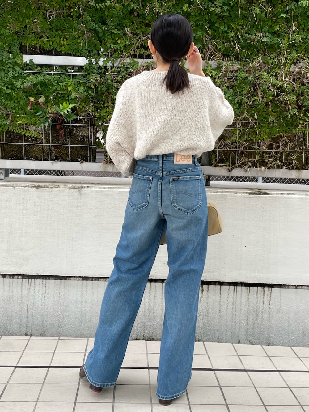 ブルー系のデニムパンツ、ブラウン系のブーツ、ホワイト系のニット/セーターを着用したレディースの秋コーディネートの8枚目の写真