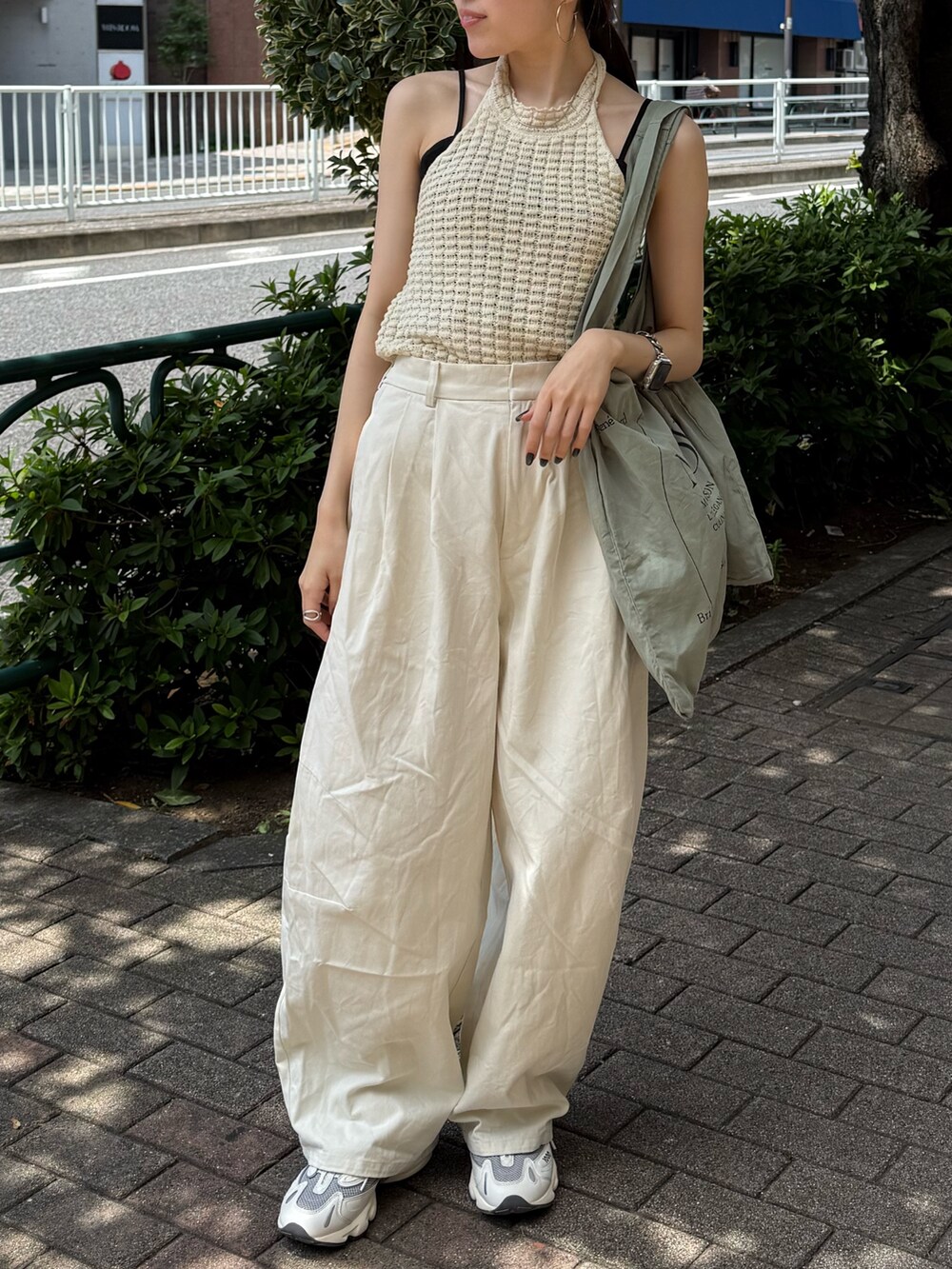 ホワイト系のチノパンツ、グリーン系のトートバッグ、ホワイト系のタンクトップを着用したレディースの夏コーディネートの6枚目の写真